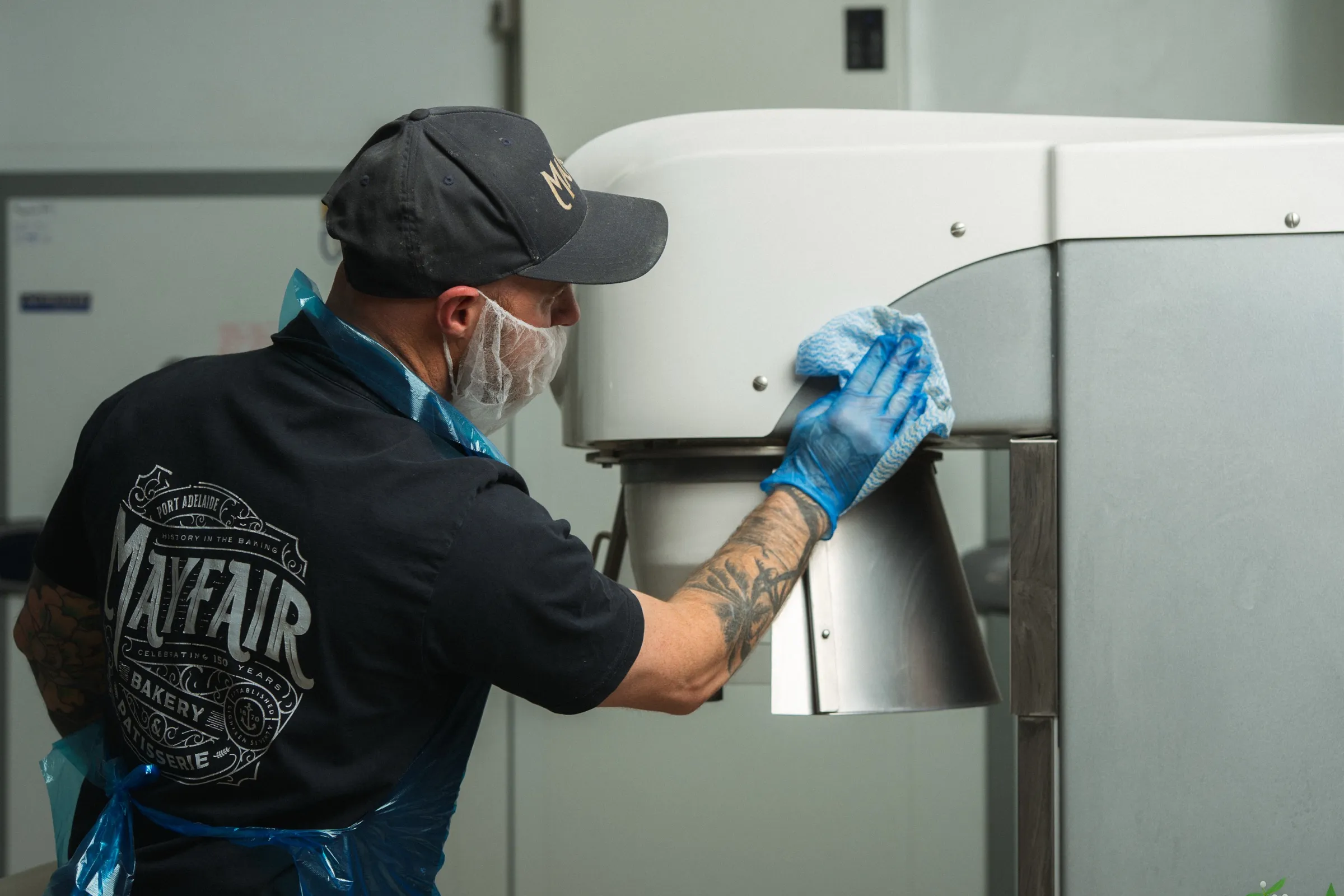 A Mayfair Bakery team member wiping down a mixer